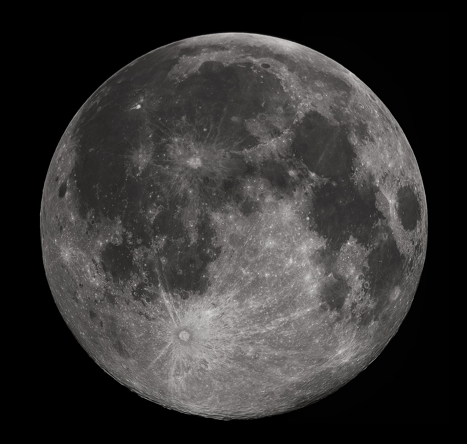 A telescopic photograph of the full moon on a black sky, the disc lit right to the edge with no shadowed rim anywhere. Smooth dark grey plains spread across a broad part of the face; the rest is paler and crowded with overlapping round craters. One crater near the edge of the disc throws long bright rays outward across much of the surface.