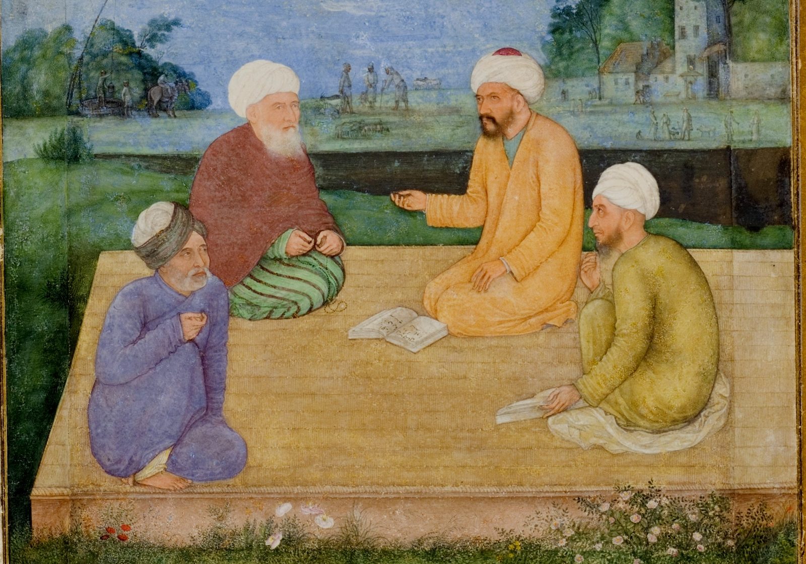 A Mughal miniature on aged paper, in warm greens and blues. Four bearded men in turbans sit cross-legged on a low raised platform in a garden, facing each other in a loose square. A small book lies open on the platform between them. The man on the right, in a saffron robe and white turban with a red crown, holds one hand out over the book with his fingers pinched together as if setting out a point; the older man opposite, in a dark red cloak and green striped trousers, listens with his hands in his lap. A man in blue kneels at the left, and a man in olive green sits at the right with his back half turned, a closed book held flat under his hand on the platform. Behind them a low dark hedge, a green field with small figures at work, and pale houses and trees against a wide sky.