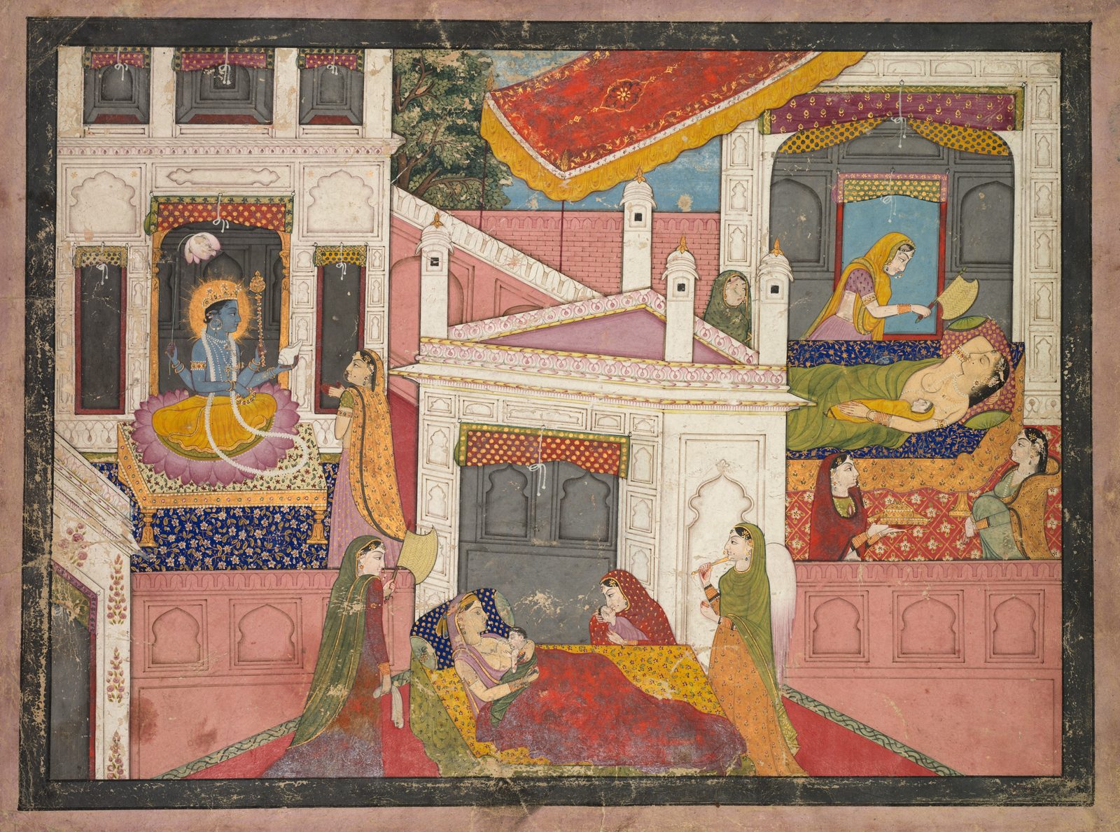 A Pahari painting on aged paper, wider than it is tall, inside a dark speckled border and a pale pink margin. Inside a white marble palace, three scenes sit at once. At the upper left, in a dark arched niche, a blue-skinned four-armed figure with a golden flaming halo sits on a pink lotus set on a low platform spread with blue and gold cloth, wearing a yellow lower garment and long strands of pearls, one hand raised; a woman in an orange and gold veil stands before him. At the lower centre, on a red and yellow floor spread, a woman in a blue patterned bodice reclines holding a newborn against her chest, a second woman in red sits beside her with a child, and attendants stand around them, one holding a round fan, one raising a slender yellow pipe to her lips. At the upper right, under a purple and gold valance, a woman in green lies on a bed with a blue floral coverlet while an attendant fans her and two others sit at the foot of the bed with a covered gold dish. A red and gold awning is stretched above against a patch of blue sky, with a green tree behind.