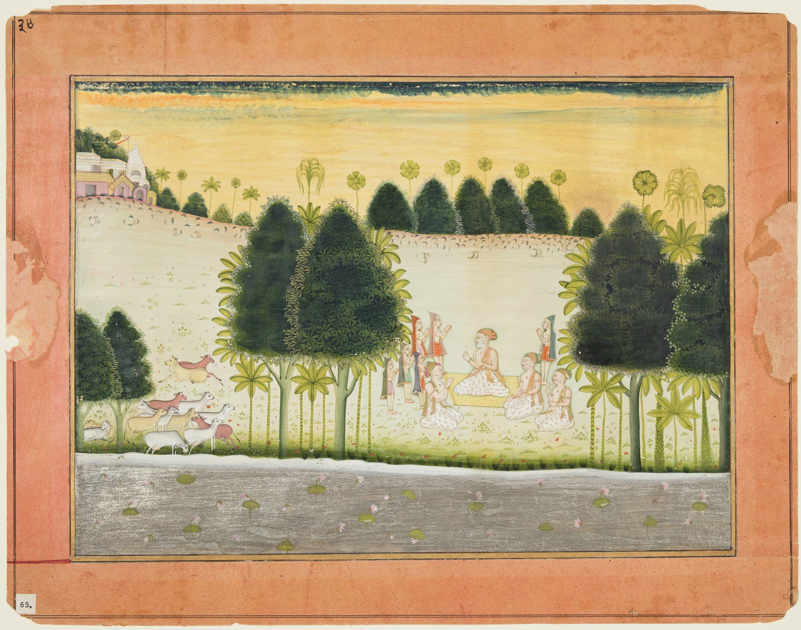 An Indian miniature painting mounted on an aged orange-pink album page. In a pale green meadow between dark rounded trees and slender plantain palms, a group of men sits in the open. At the centre an elderly man with a white beard, an orange and gold turban and a white dhoti printed with small red flowers sits on a yellow cushion worked with gold scrollwork, holding a small pale flower up in one hand. Three other white-bearded elders in the same printed white cloth kneel on the grass around him, one with his palms raised in front of him in the middle of speaking, another holding up a pink blossom. Behind them stand younger cowherds in striped hooded coats and short patterned tunics, one carrying a shallow bowl. Cattle graze at the left, a white shrine stands on a rise in the distance, and a silver river with lotus pads runs across the foot of the page.