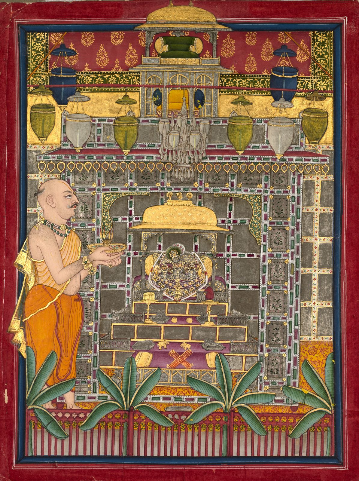 A small Rajput painting, taller than it is wide, worked in gum tempera with silver and gold. A ruler dressed as a priest stands at the right and holds up a lamp with five lit flames towards a shrine kiosk, where three small metal images stand on an altar with Krishna in the middle and a consort on each side. Glass lamps hang in rows from the ceiling above him, and toys are set out on the steps below the altar: brass elephants, silver cows, balls and a board for pachisi.