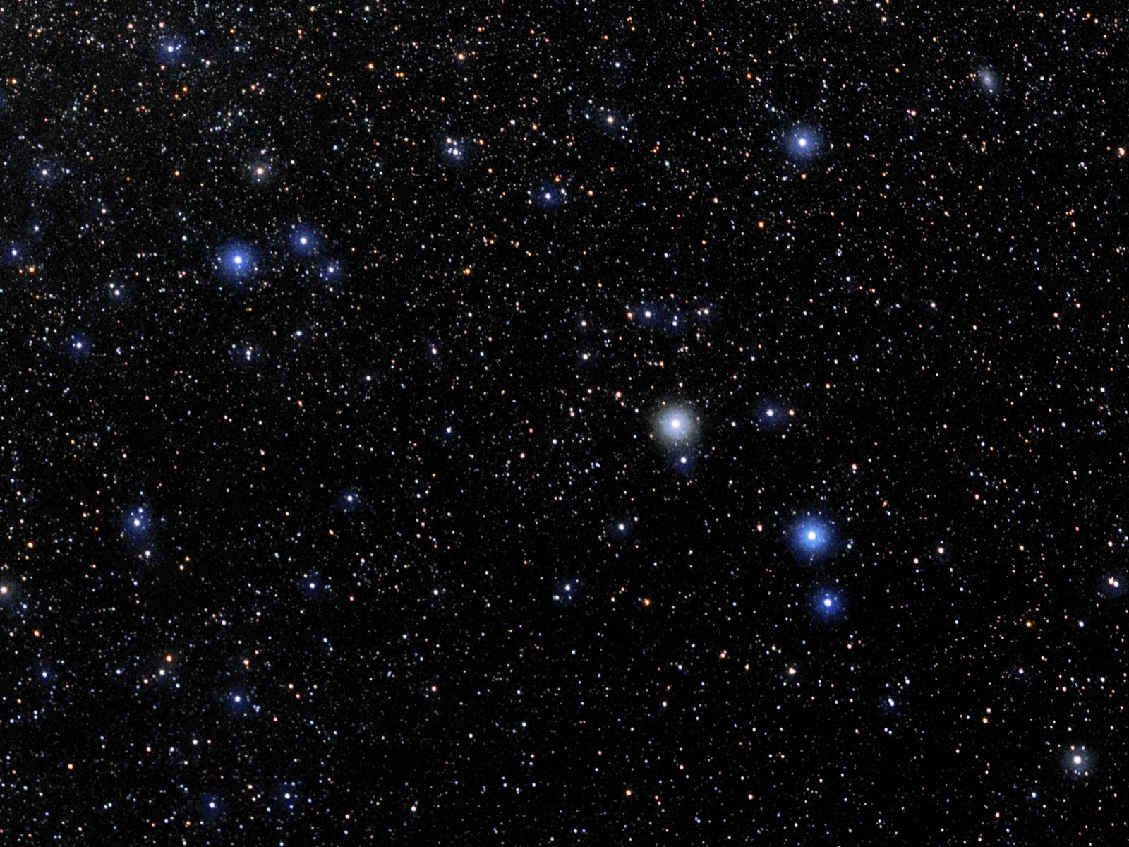 A wide-field night-sky photograph: thousands of faint white and blue stars on black, thinning towards the lower right. One warm yellow-white star stands out at the upper right with a brighter blue-white star and a fainter companion below it; at the left edge sits the tight blue knot of the Pleiades cluster, with a small thread of red nebulosity in the top corner.