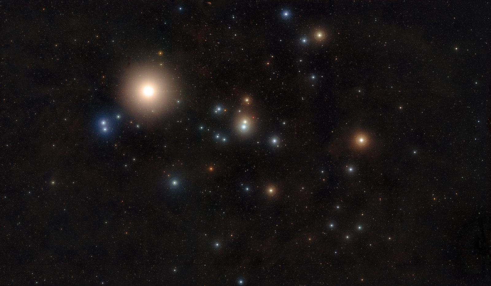 A wide-field photograph of a dark star field. A large, bright orange star with a broad glowing halo sits in the upper le