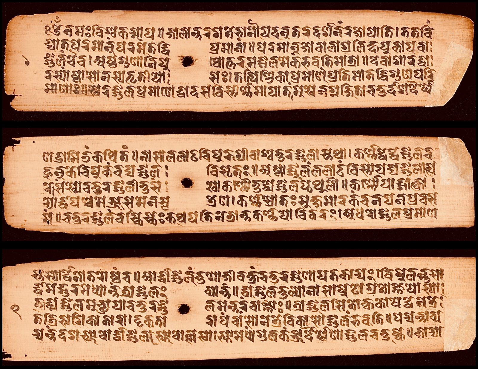Three long, narrow palm-leaf manuscript folios laid one above another and photographed against a black ground. Each pale tan leaf carries about five lines of Sanskrit written in dark brown ink in an old Nepalese script, with a round string hole punched through the middle of the leaf and a small numeral in the left margin. The edges are chipped and a pale strip of repair paper covers the right end of the leaves.