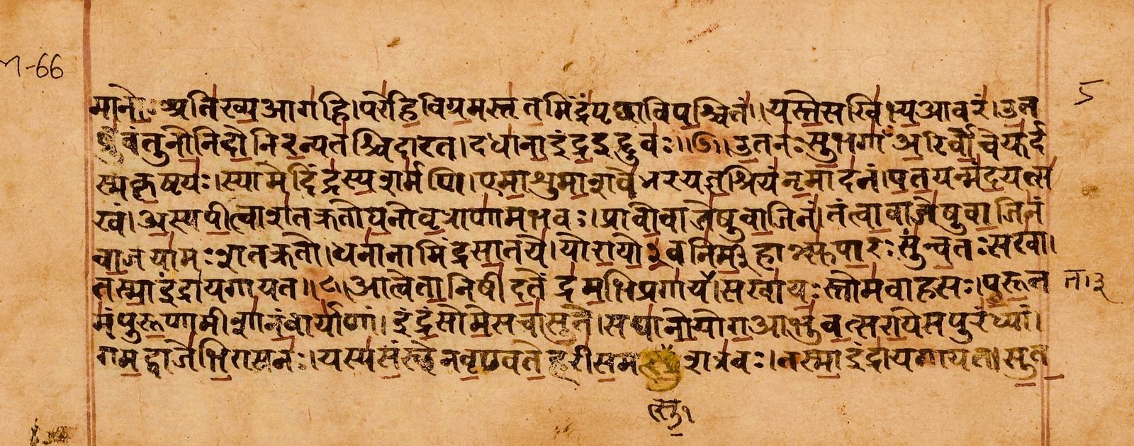 A wide manuscript folio of warm tan paper, photographed flat and filling the frame. Eight lines of Sanskrit in Devanagari run across it in dark brown ink, with short red accent strokes standing above the letters, and a single ruled red line closes the text block at each side. The mark M-66 is inked in the upper left margin and a numeral sits in the upper right. The paper is stained and foxed, and near the bottom centre a patch of yellow correction pigment covers a word, with one syllable rewritten below the line.